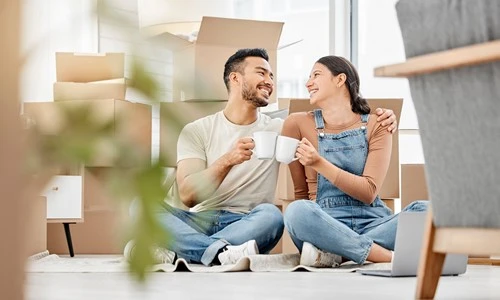 Hypothek Waadt: Lächelndes Paar trinkt Kaffee in ihrem mit einem Hypothekendarlehen gekauften Haus